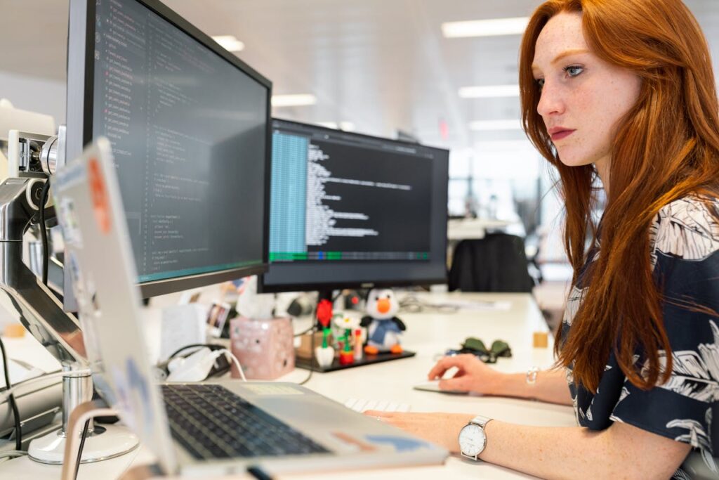 pexels-photo-3861958 A focused female software engineer coding on dual monitors in a modern office.